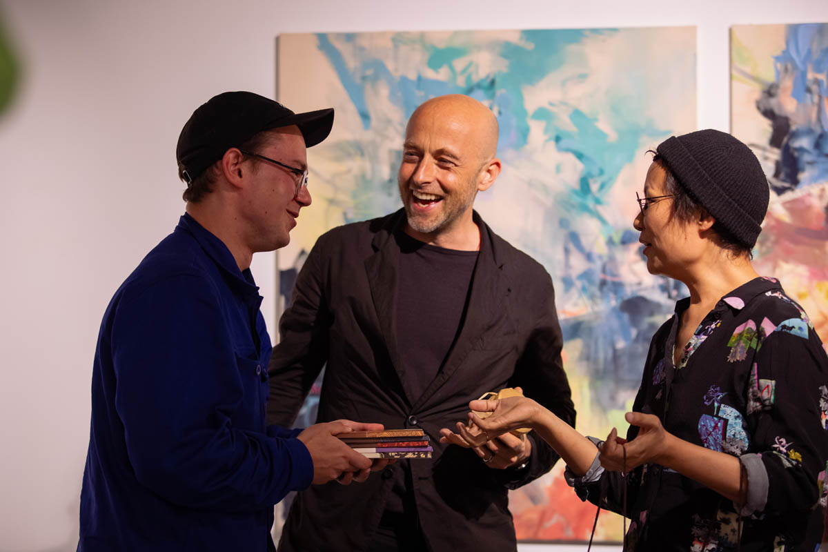 Trzy postaci na tle abstrakcyjnego obrazu