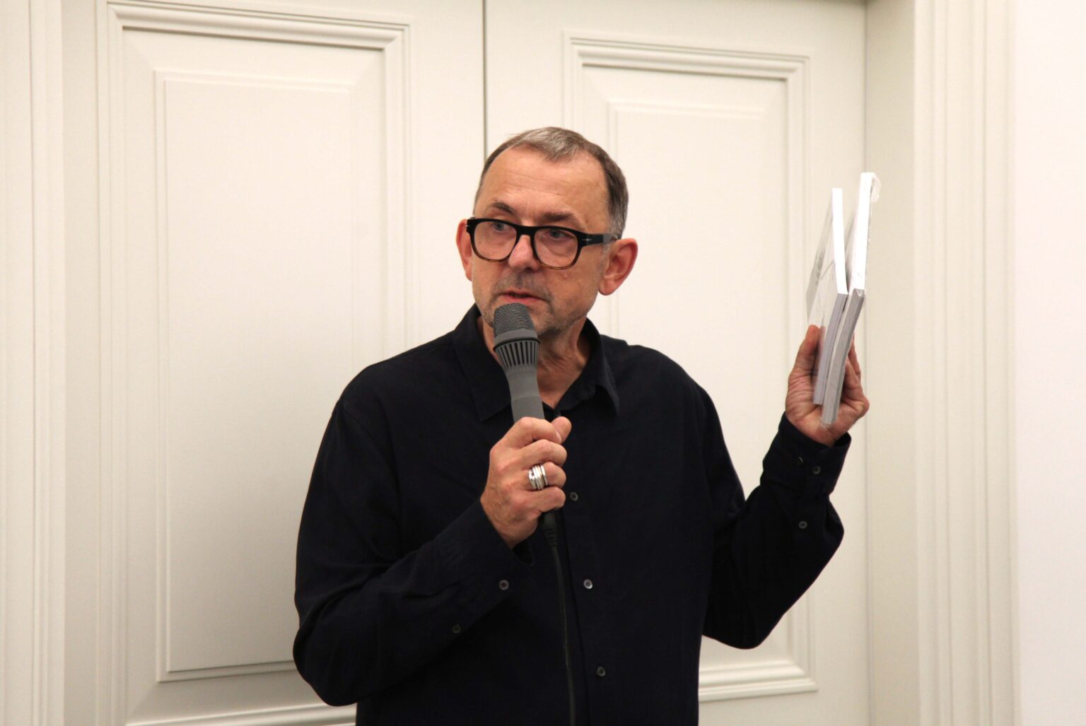 Mężczyzna w okularach mówiący do mikrofonu