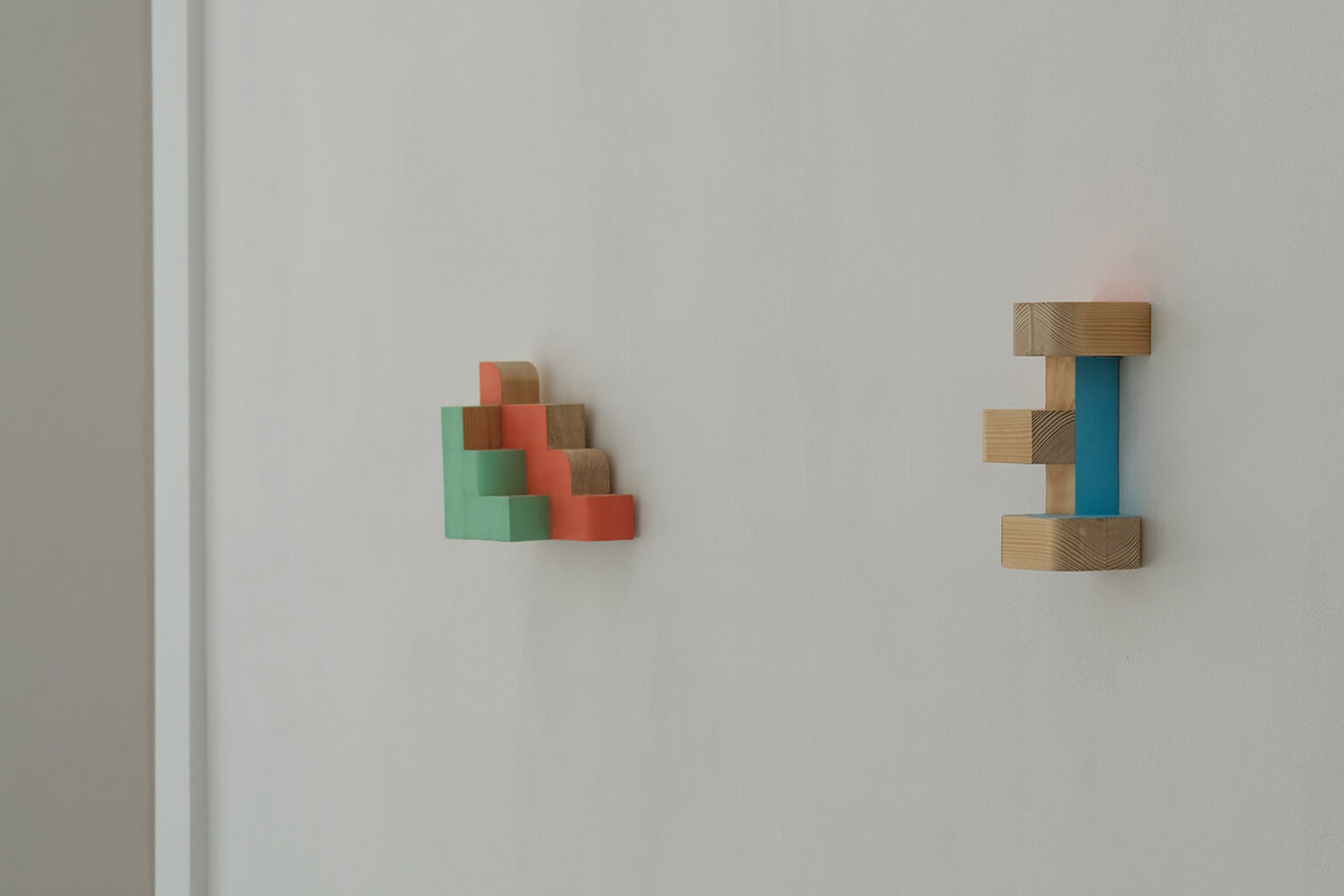 Kolorowe, geometryczne formy przestrzenne na ścianie galerii