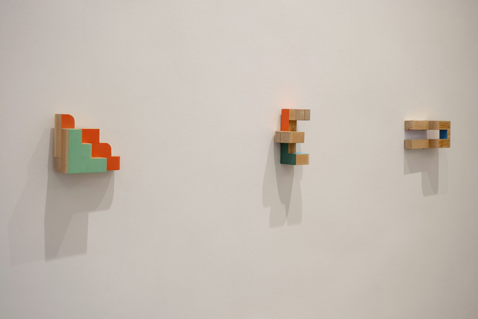 Kolorowe, geometryczne formy przestrzenne na ścianie galerii