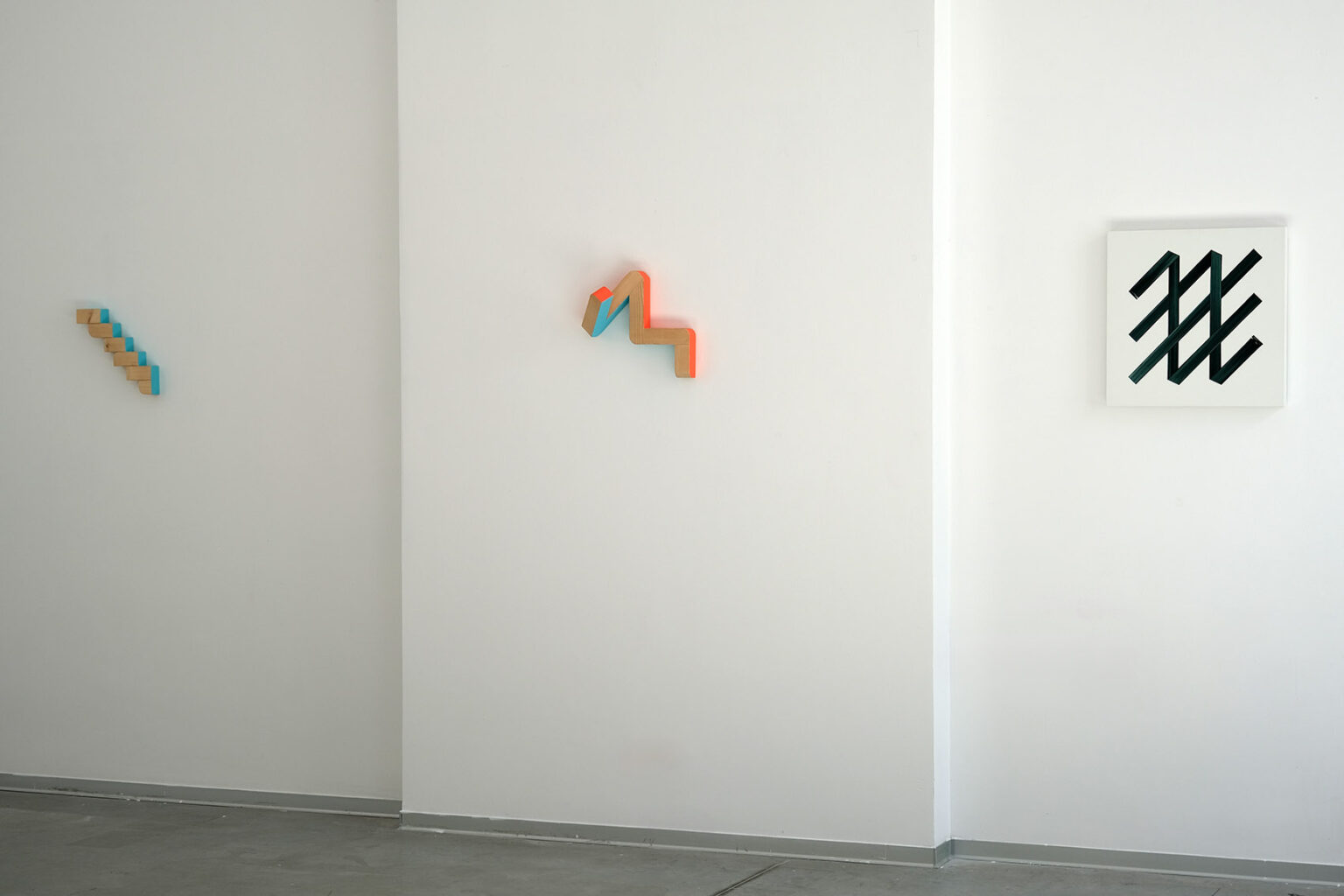 Kolorowe, geometryczne formy przestrzenne na ścianie galerii