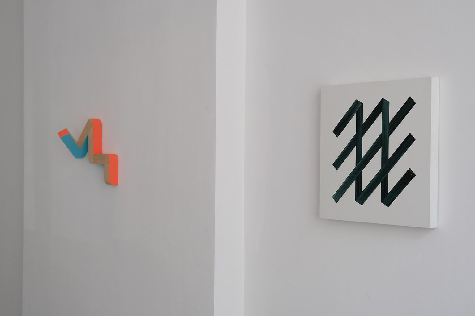 Kolorowe, geometryczne formy przestrzenne na ścianie galerii