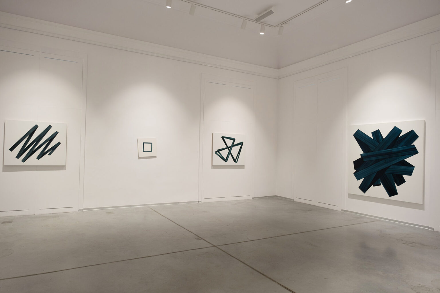 Kolorowe, geometryczne formy przestrzenne na ścianie galerii