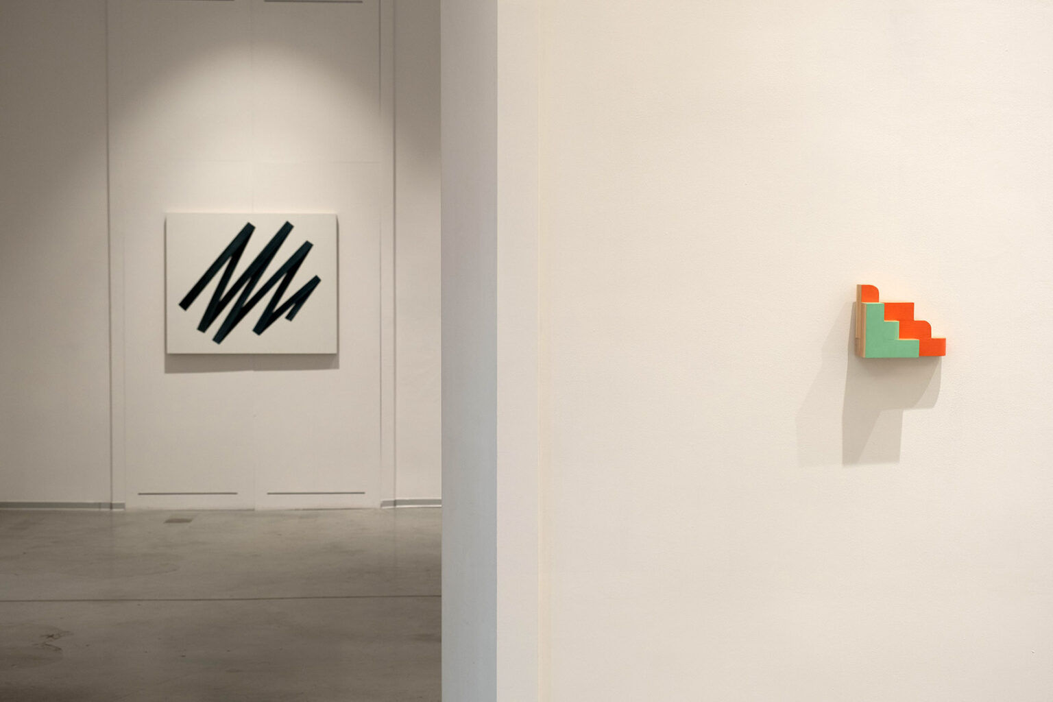 Kolorowe, geometryczne formy przestrzenne na ścianie galerii