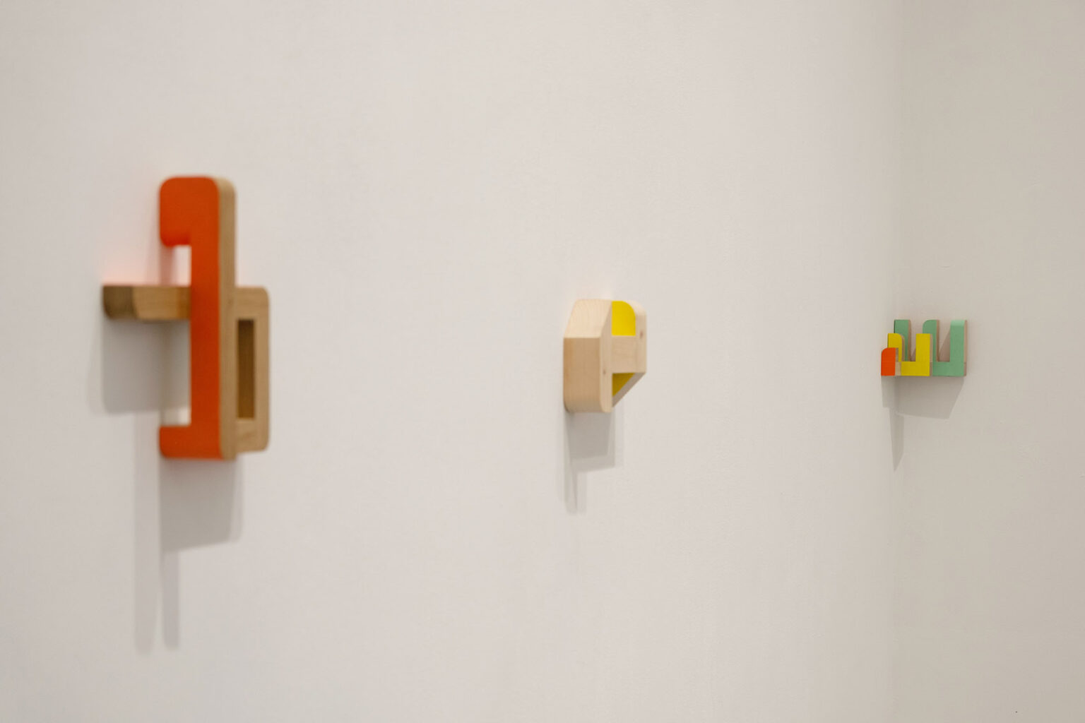 Kolorowe, geometryczne formy przestrzenne na ścianie galerii