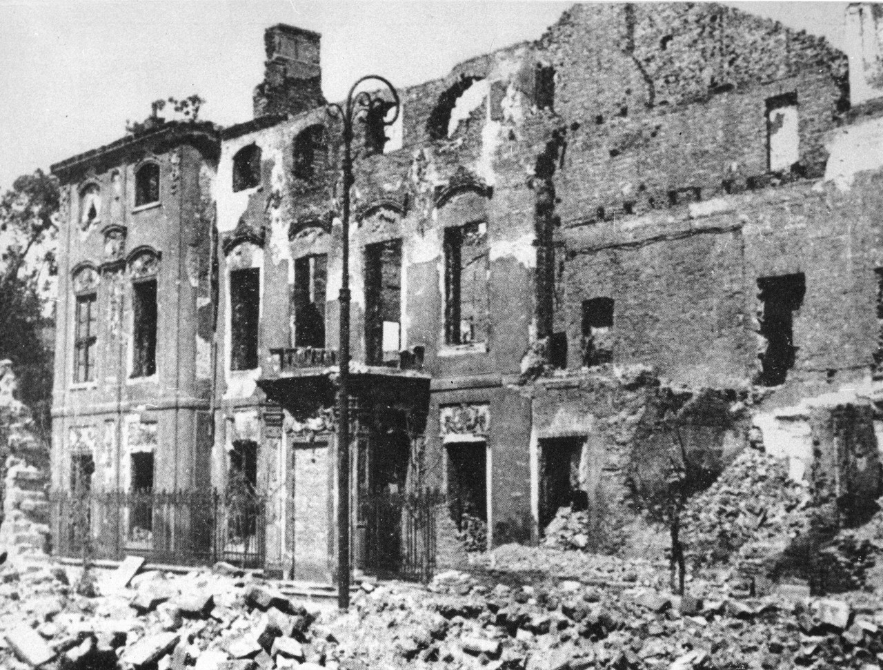 Zruinowany, pozbawiony dachu budynek, pod ścianami zalegają hałdy gruzu