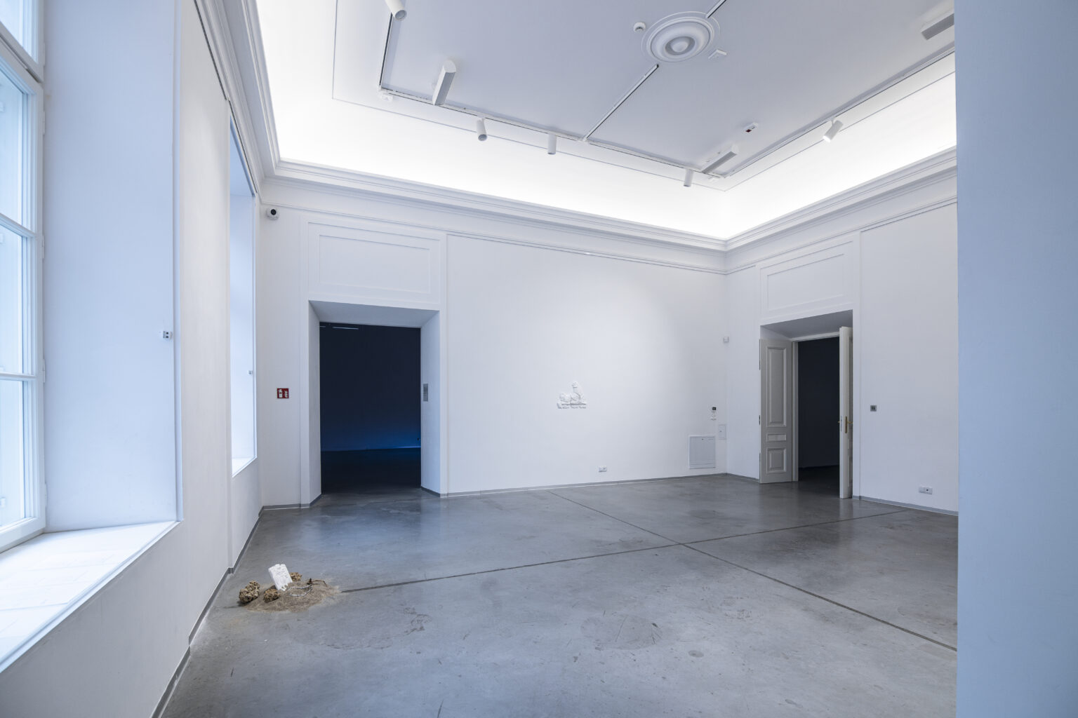 Widok sali galerii z zawieszonymi gipsowymi płaskorzeźbami wygenerowanymi przez sztuczną inteligencję