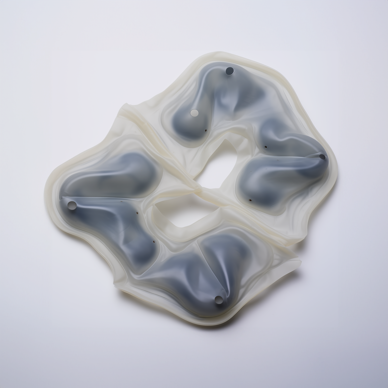 W centralnej części zdjęcia nieregularna, półprzezroczysta forma z czarnymi elementami umieszczonymi wewnątrz tej formy. Obiekt wygenerowany przez sztuczną inteligencję