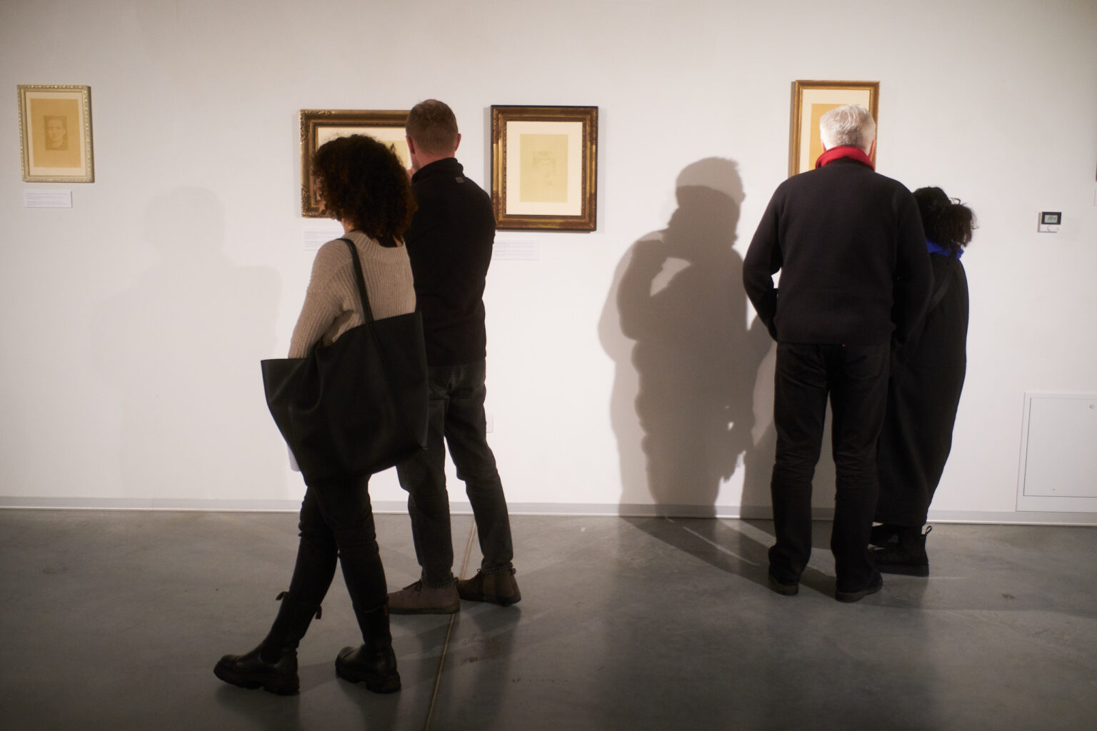 Otwarcie wystawy w galerii sztuki. Ludzie oglądają grafiki umieszczone na ścianach