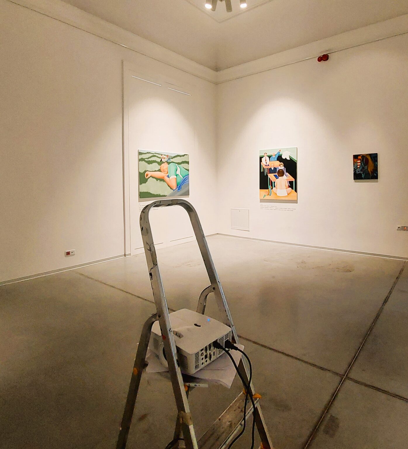 Drabina z projektorem w sali z białymi ścianami.