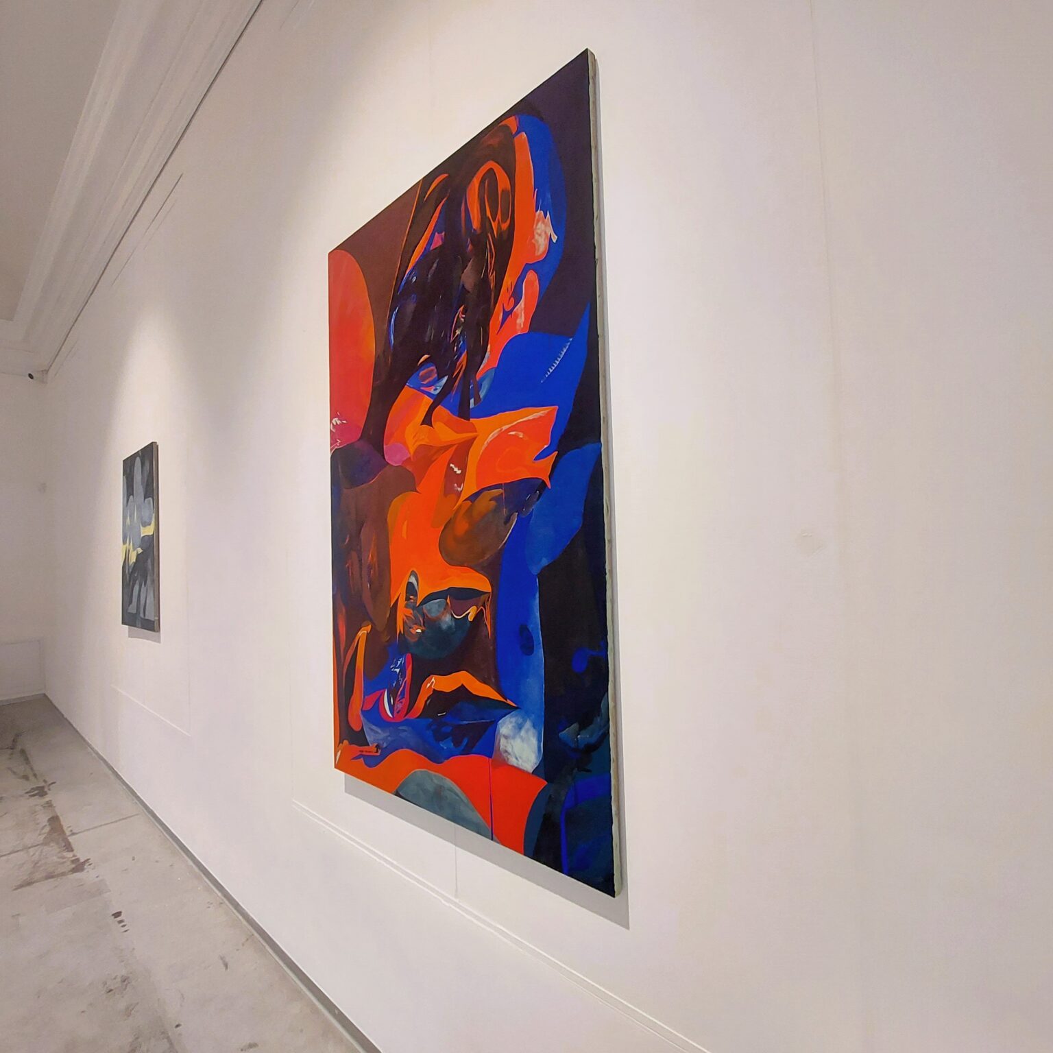 Kolorowe obrazy wiszące na białych ścianach.