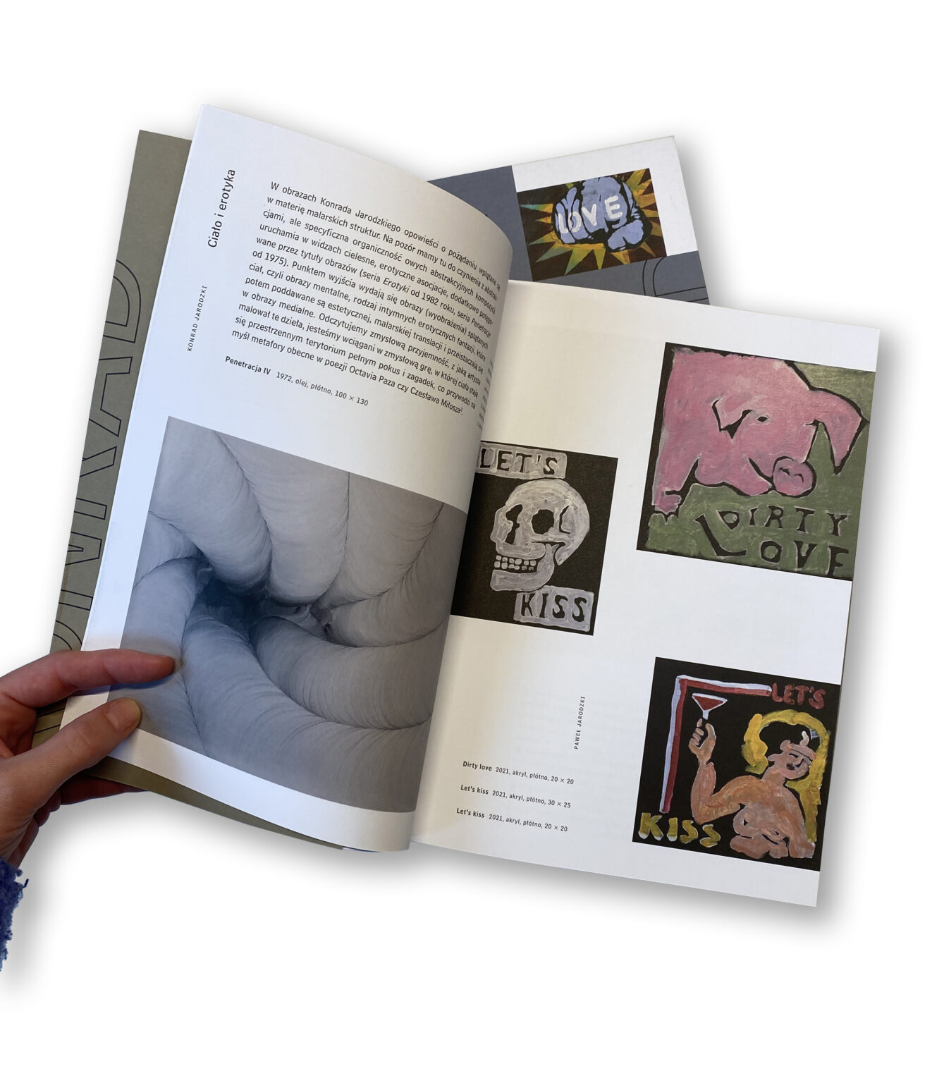 ręka otwiera książkę na jednej z rozkładówek.