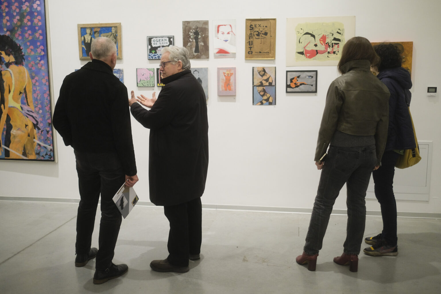 Widzowie wystawy stoją tyłem na tle prac Pawła Jarodzkiego.