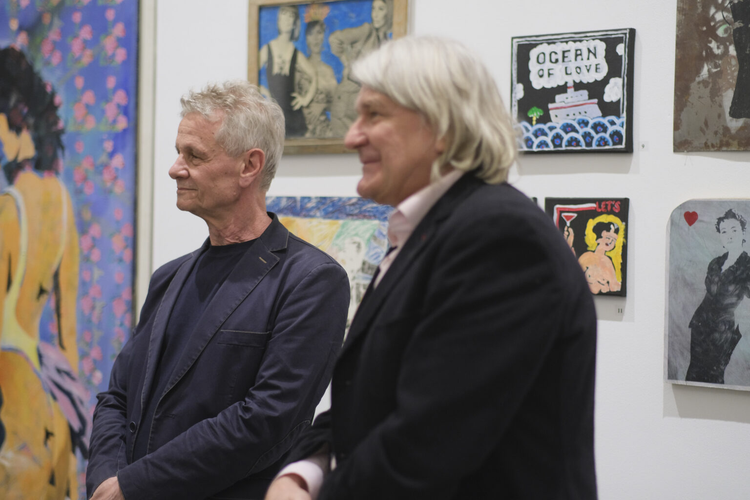 Dyrektor galerii prof. Paweł Nowak oraz kurator wystawy Marek śnieciński stoją na tle obrazów Pawła Jarodzkiego.