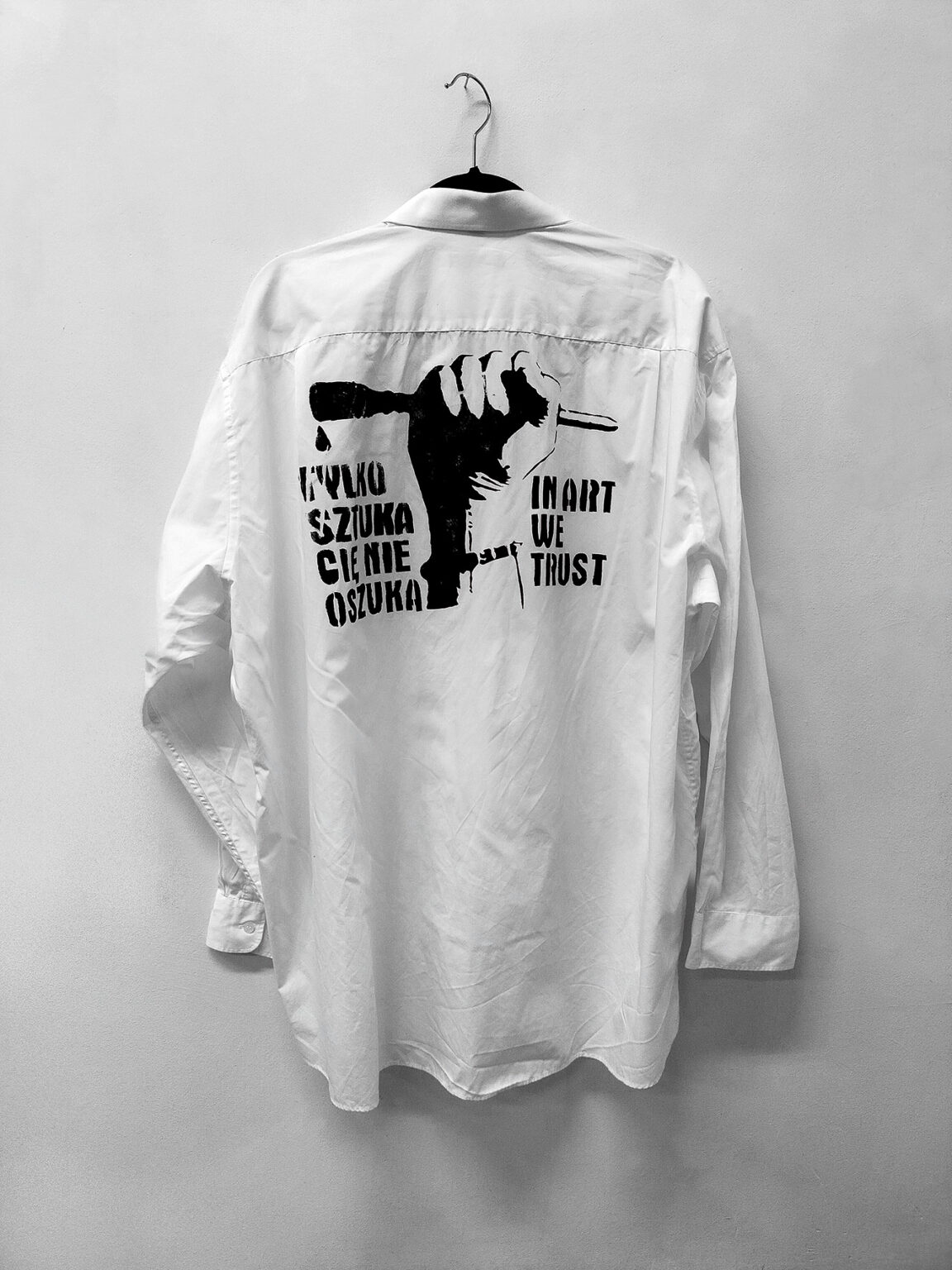 Reprodukcja pracy Pawła Jarodzkiego, pod tytułem "Tylko sztuka cię nie oszuka", z 2001 roku, koszula XXL, akryl, szablon