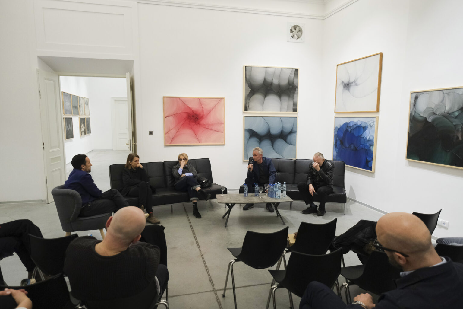 Na tle obrazów Konrada i Pawła Jarodzkich siedzą na czarnych kanapach prelegenci debaty.