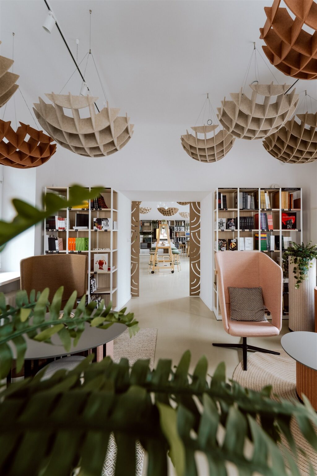Nowocześnie umeblowane, jasne wnętrze z regałami pełnymi książek i kulistymi ozdobami podwieszonymi pod sufitem