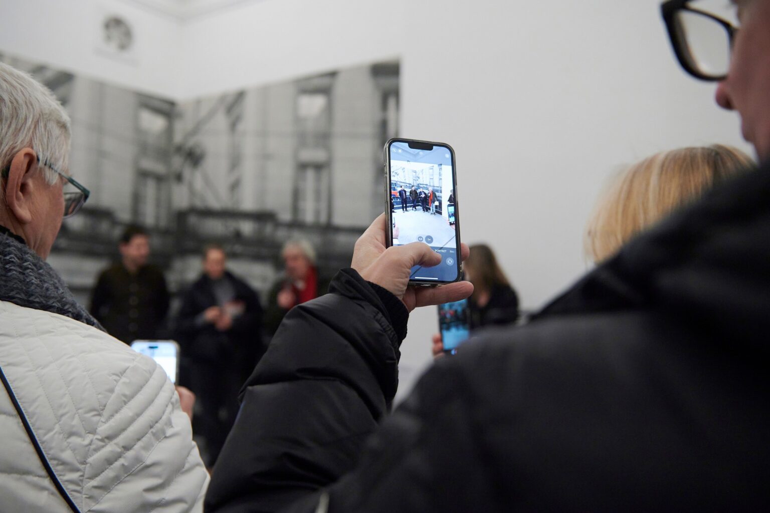 zdjęcie męskiej dłoni robiącej zdjęcie telefonem kilku osobom