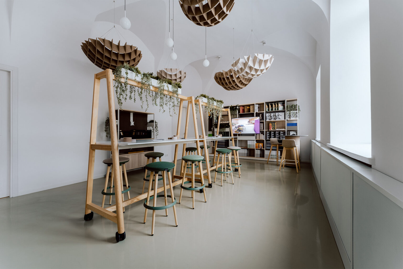 Nowocześnie umeblowane, jasne wnętrze, kulistymi ozdobami podwieszonymi pod sufitem