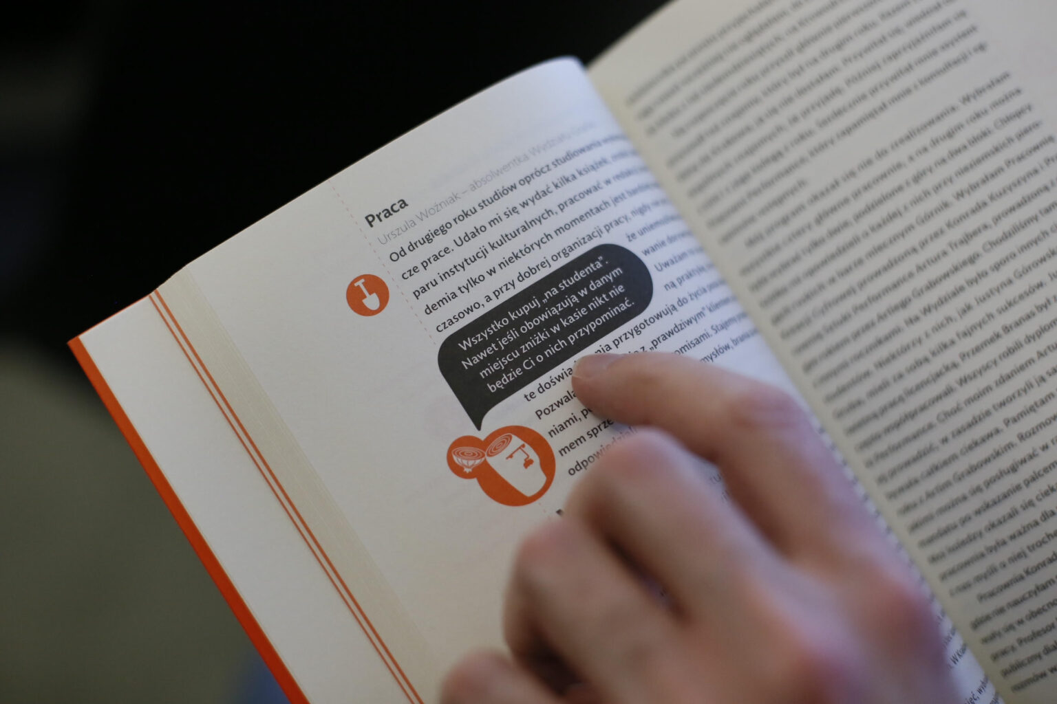 Fragment strony książki. Tekst jest nieczytelny, ale widoczny jest palec wskazujący na konkretne miejsce.