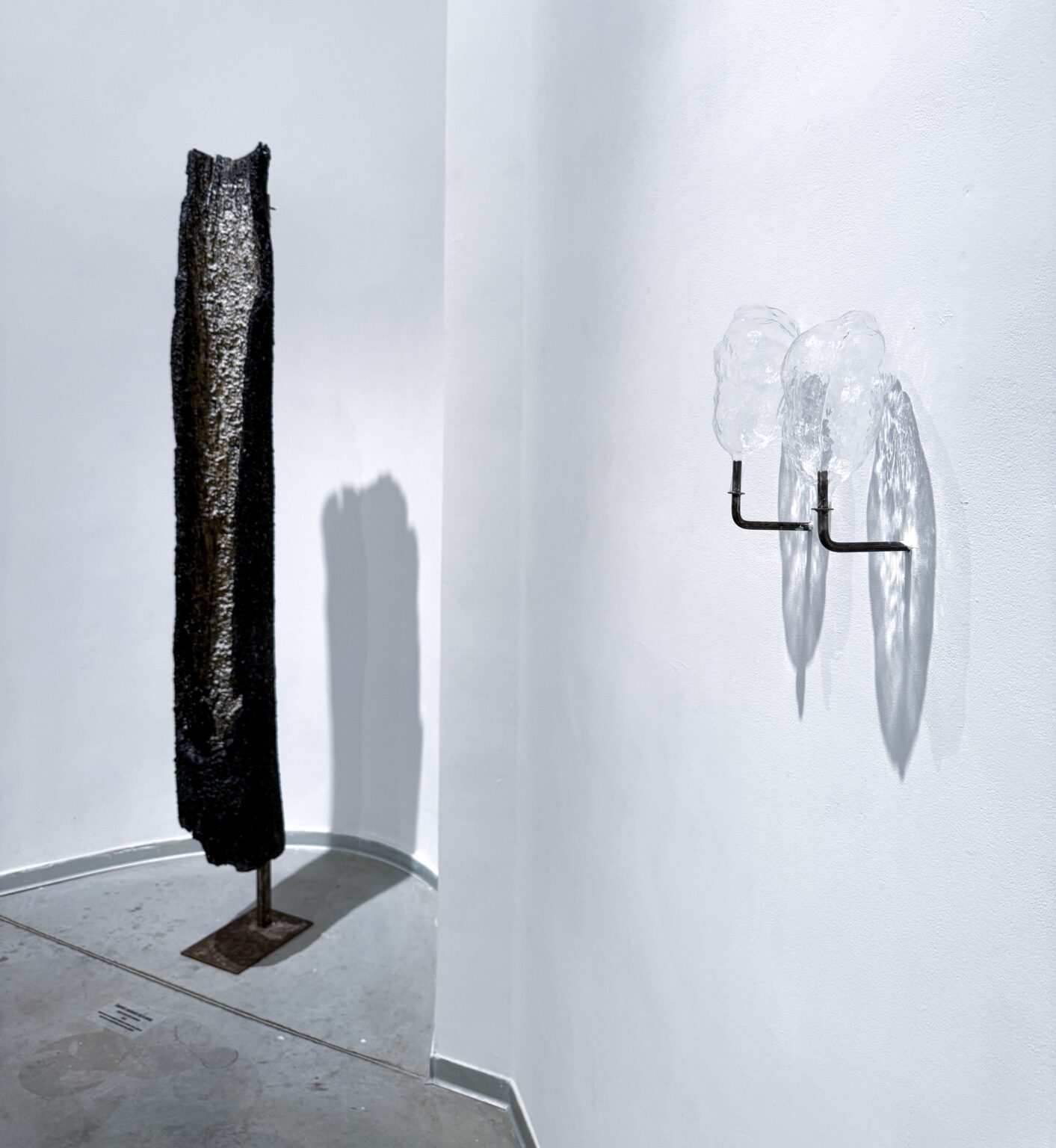 dwa obiekty szklane na ścianie, obok czarna instalacja podłużna