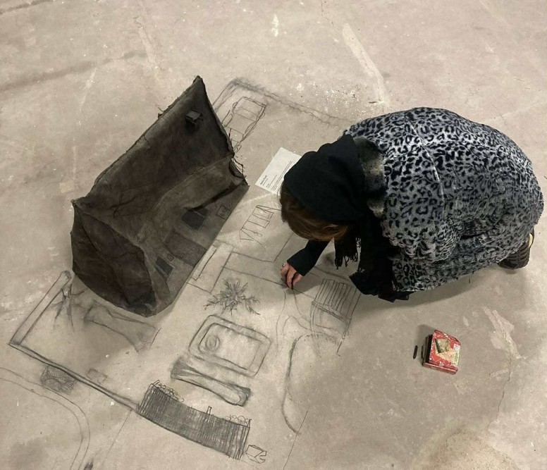 widok z góry, dziewczyna rysuje węglem na betonie plan wnętrza domu