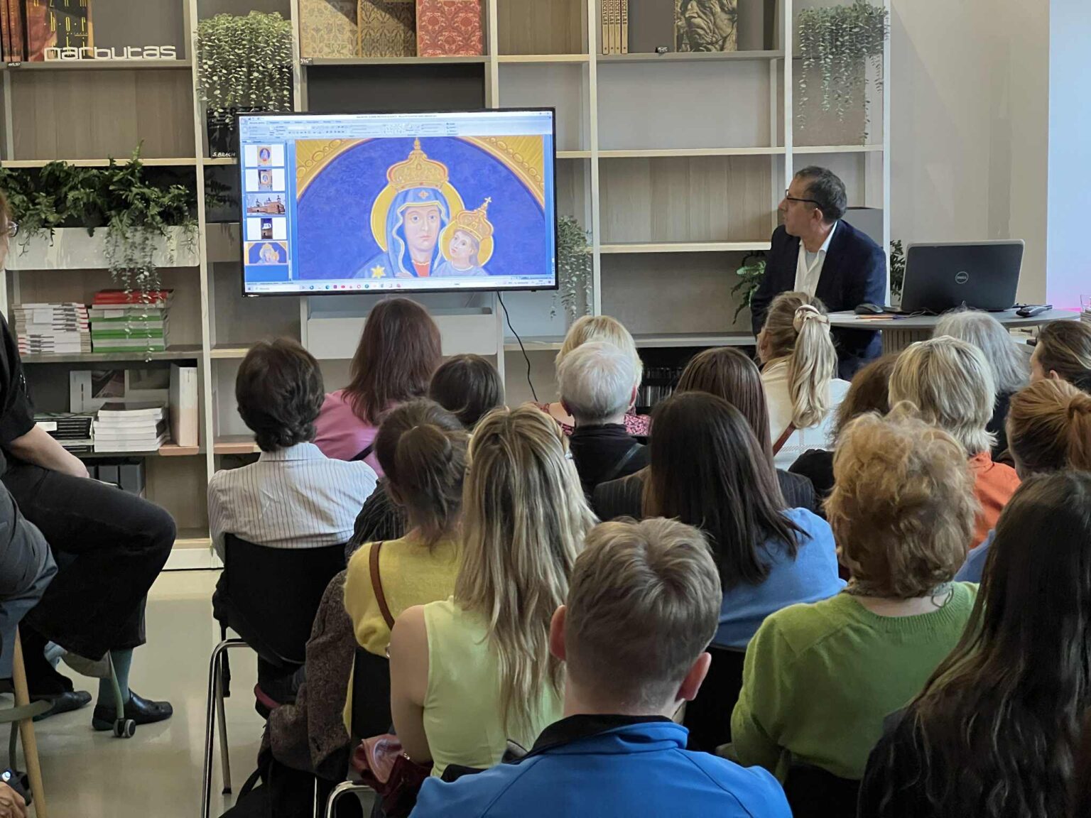 Sylwester Piędziejewski podczas wykładu, prelegent stoi przy ekranie, który wyświetla cyfrową kopię obrazu Matki Boskiej.